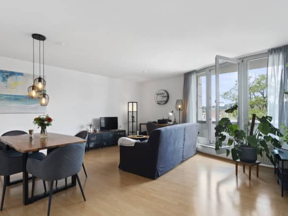 Heller, moderner Wohn- und Essbereich mit dunklem Sofa, Esstisch und grauen Stühlen - perfekt, um Ihr Zuhause in Szene zu setzen. Ideal für diejenigen, die eine Wohnung verkaufen Ravensburg mit Hilfe eines erfahrenen Immobilienmakler Ravensburg.