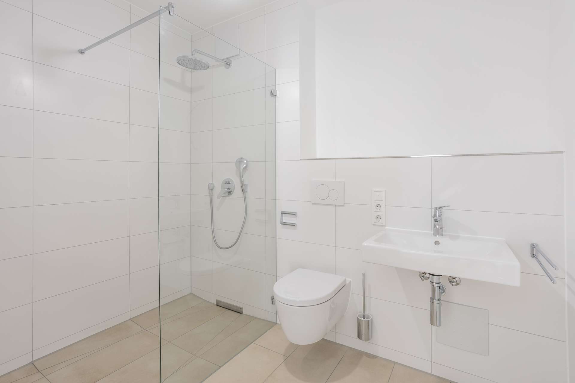 Badezimmer Modernes, minimalistisch gestaltetes Badezimmer mit einer verglasten begehbaren Dusche, einem wandhängenden WC, einem weißen Waschbecken und schlichten Armaturen. Der Raum ist mit großen weißen Fliesen und einem hellen Bodenbelag ausgestattet.