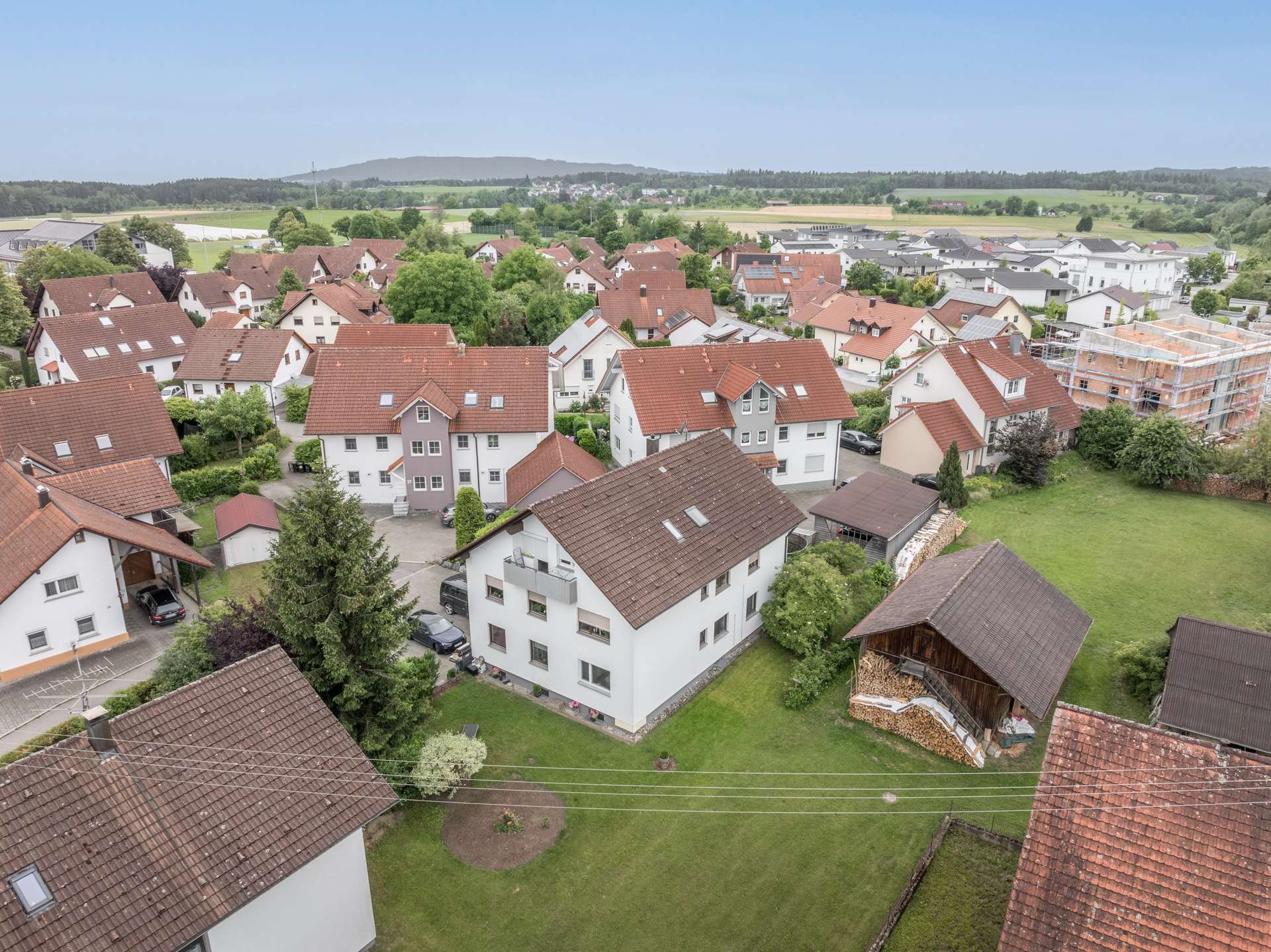 Außenansicht Luftaufnahme eines Wohnviertels mit weißen Häusern, braunen Ziegeldächern und umliegenden grünen Feldern.