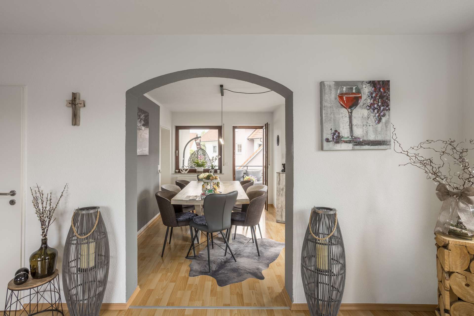 1.OG Blick durch einen Torbogen in ein Esszimmer mit einem Tisch, sechs Stühlen und einer Schiebetür, die auf einen Balkon führt.