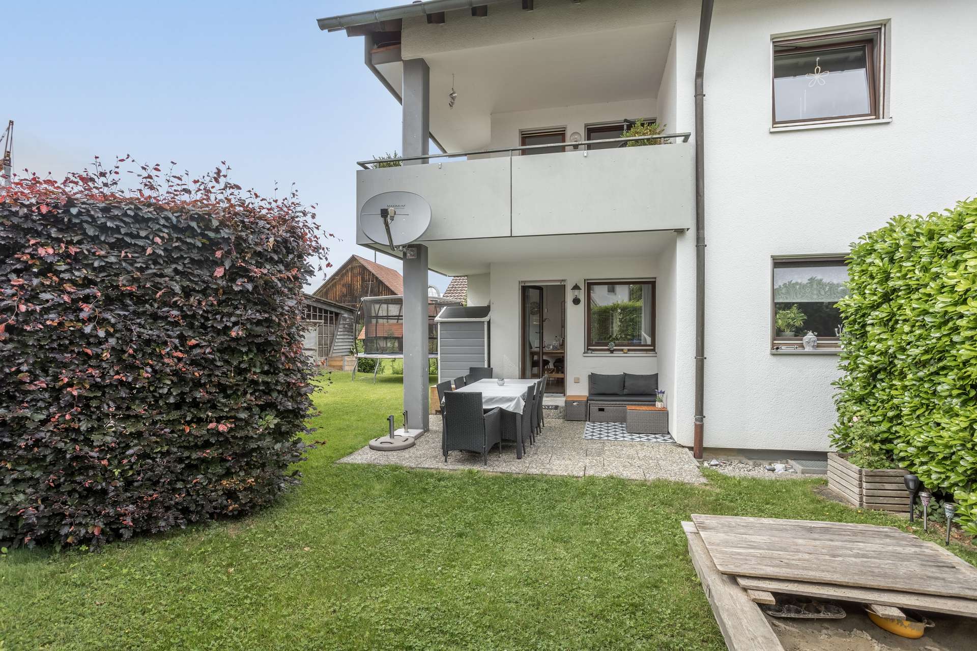 EG Terrasse im Hinterhof mit Esstisch und Stühlen, direkt neben einem Haus mit Balkon.