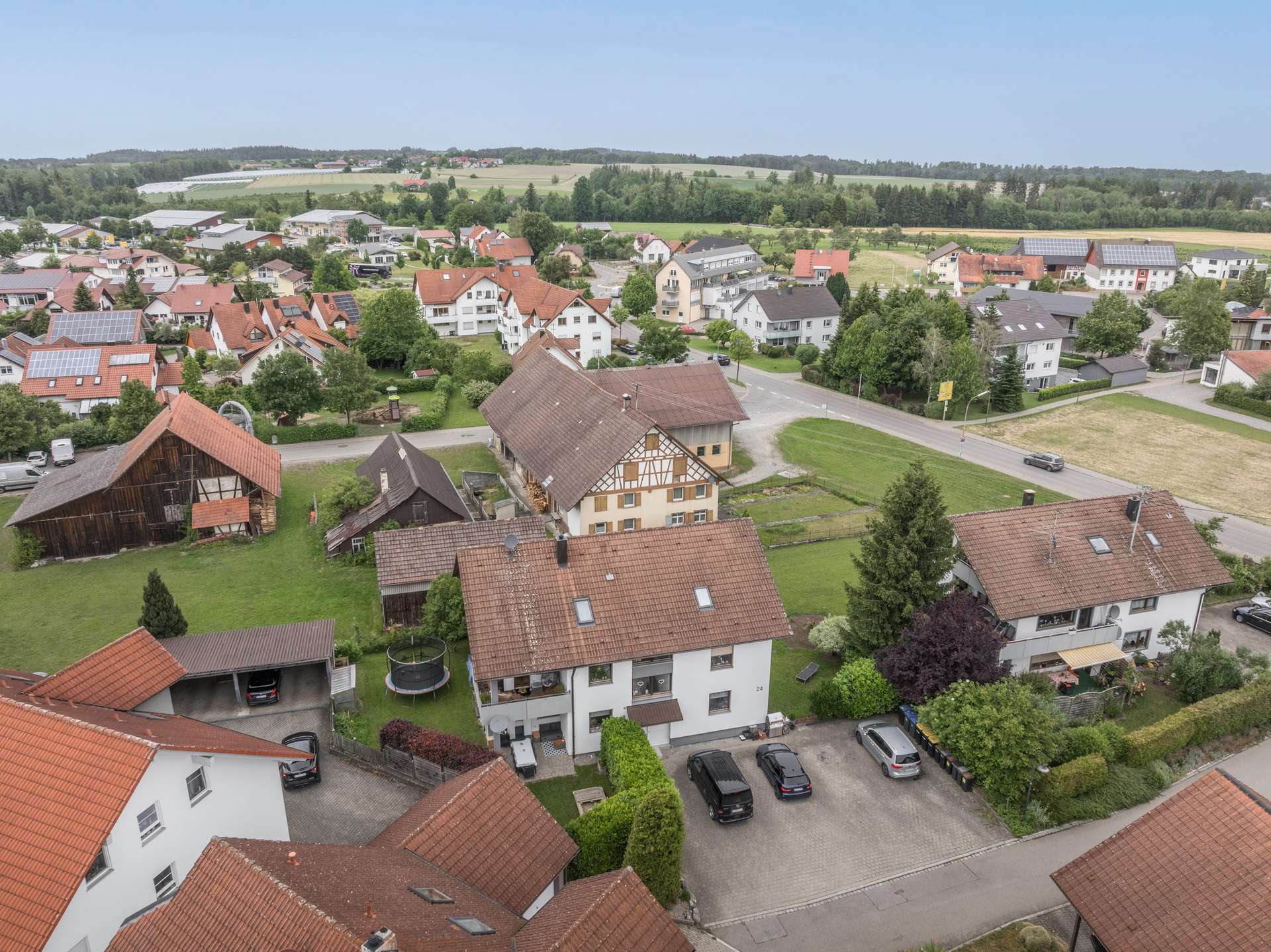 Außenansicht Luftaufnahme eines Wohnviertels in einer ländlichen Landschaft mit Häusern, Einfahrten und umliegenden Feldern.