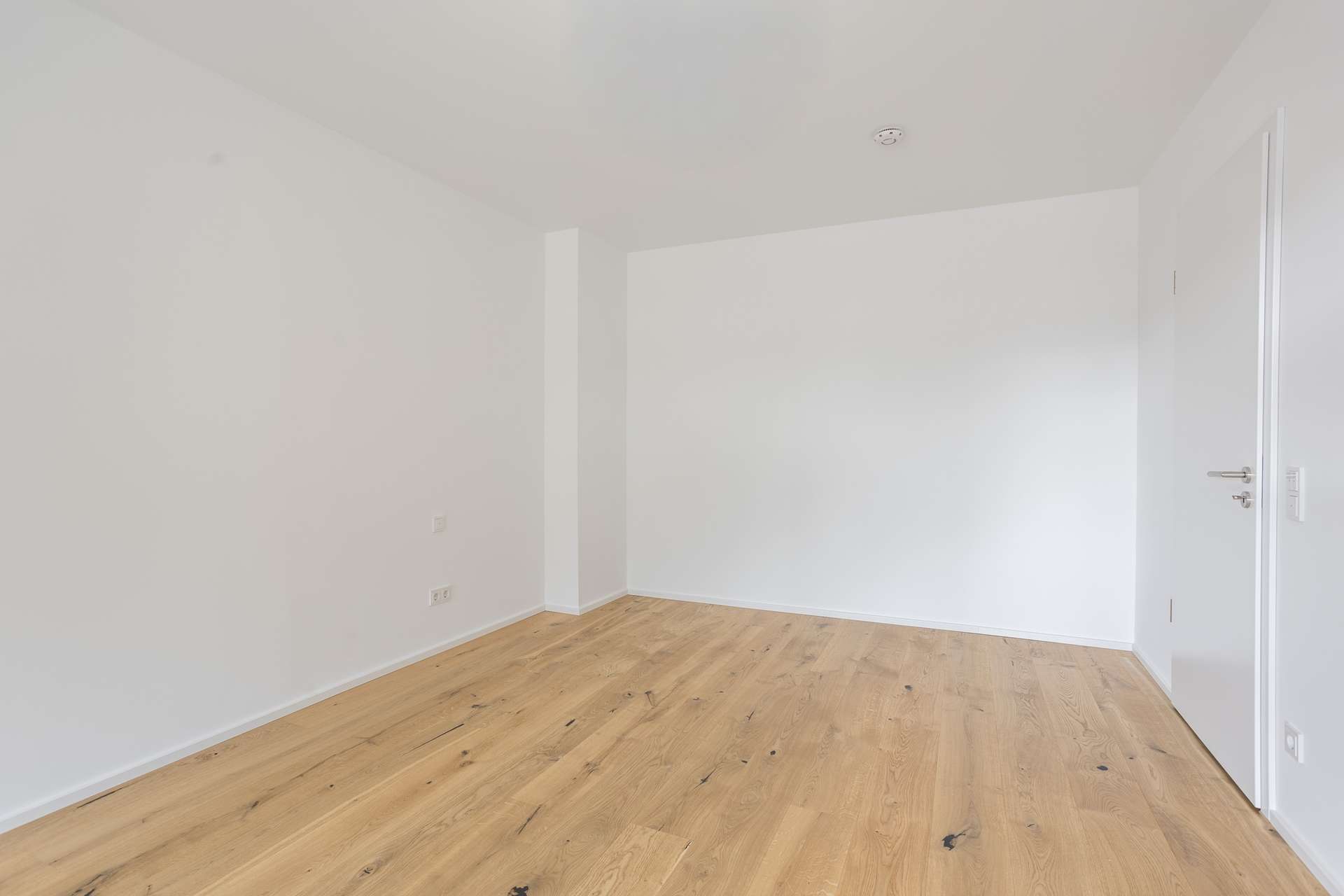 Ein leerer Raum mit weißen Wänden und hellem Holzboden. Ein leerer Raum mit weißen Wänden und hellem Holzboden.